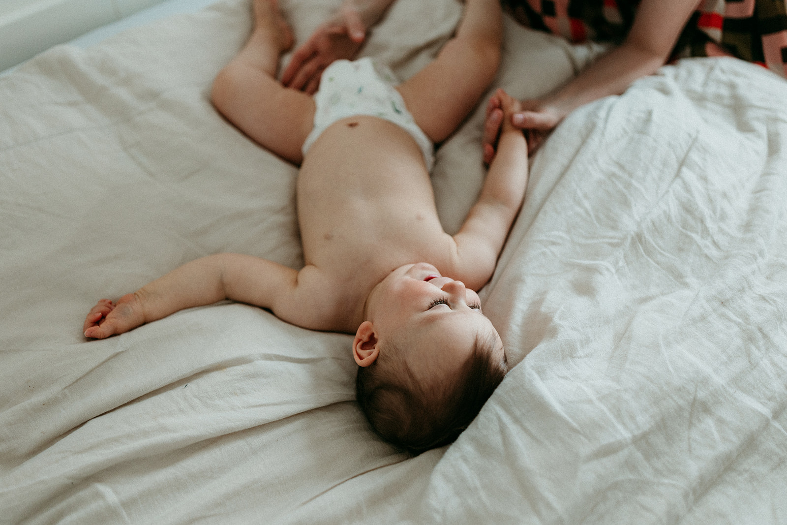 bébé nu en couche allongé sur lit