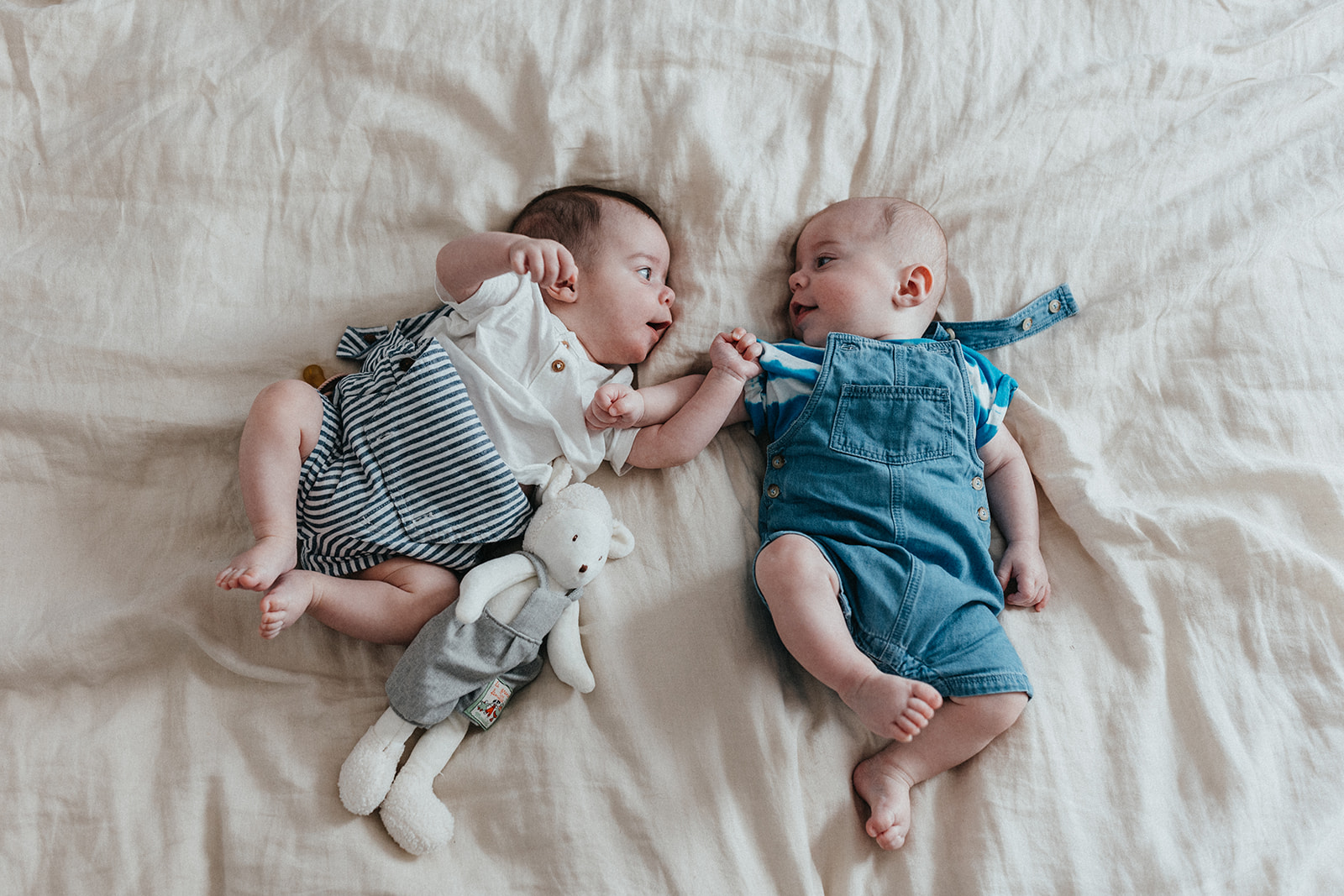 bébés jumeaux allongés sur lit qui se regardent