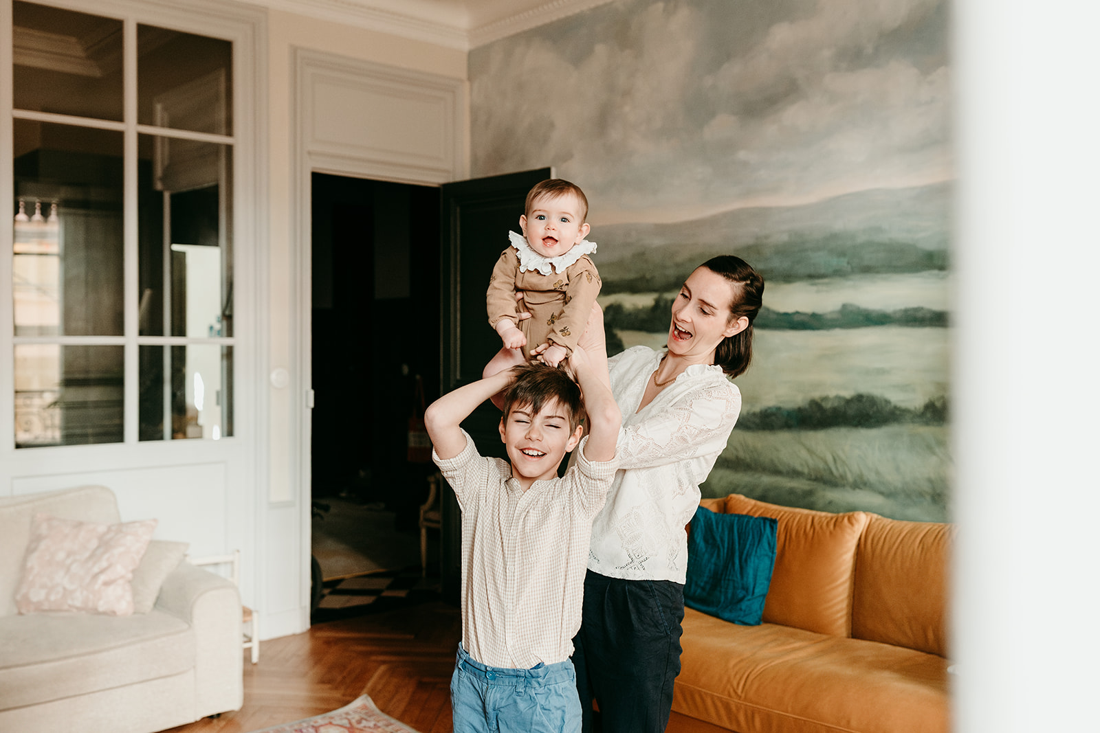 photo maman qui pose un bébé sur les épaules de son grand garçon, rires