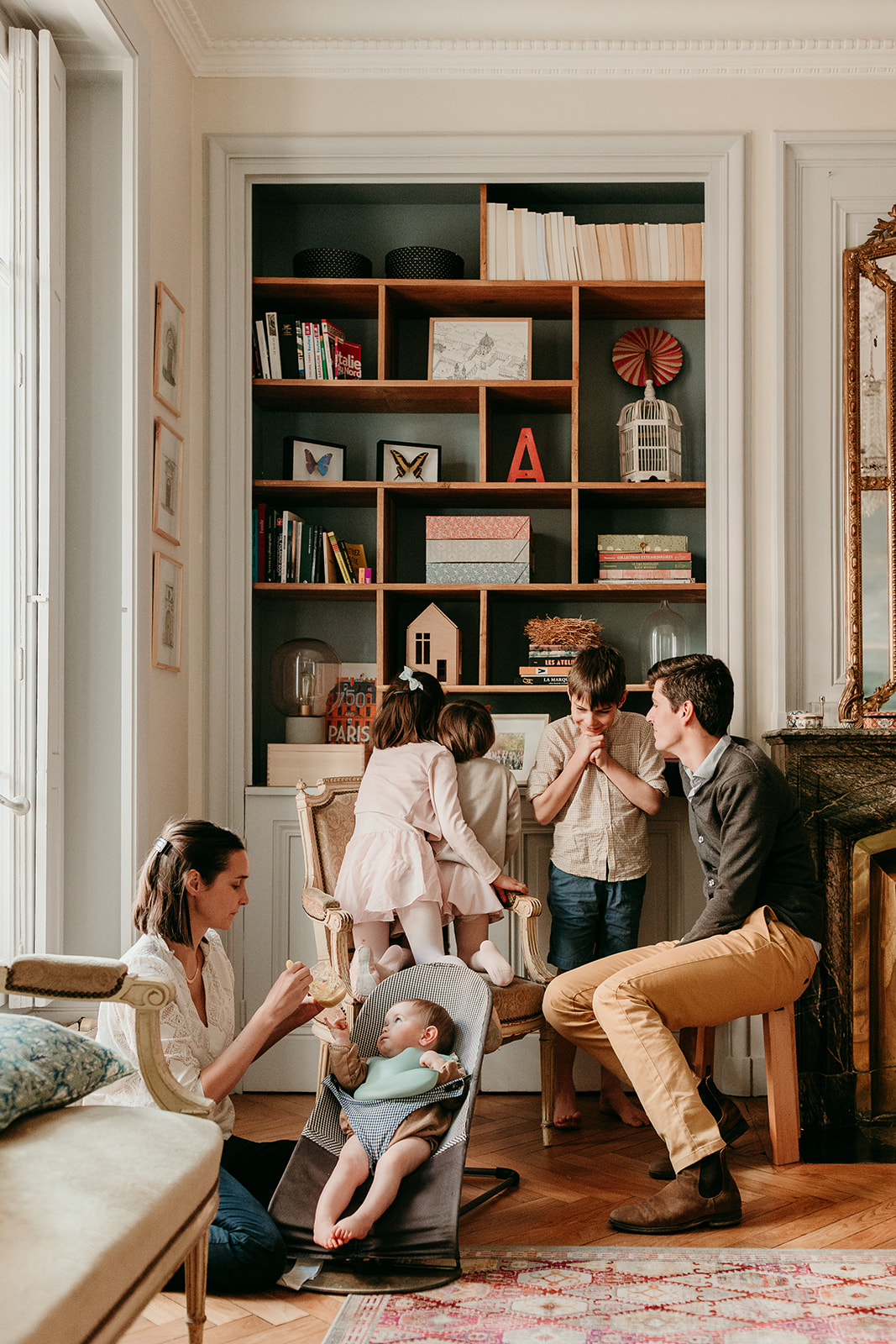 famille nombreuse dans salon qui regarde la bibliothèque de livres